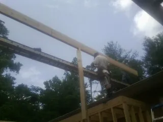 Carpenter setting a ridge beam over a new addition frame — Ice Dam Removal by Roofing Brothers in Minburn