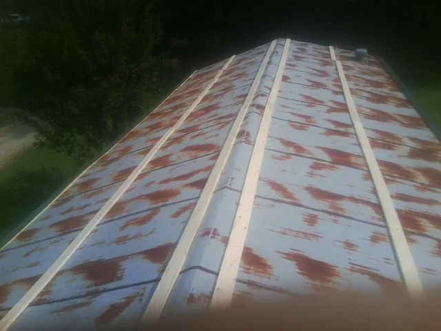 Rusted metal roof panels with new wood purlins before replacement — Storm Damage Roof Repair in Minburn by Roofing Brothers