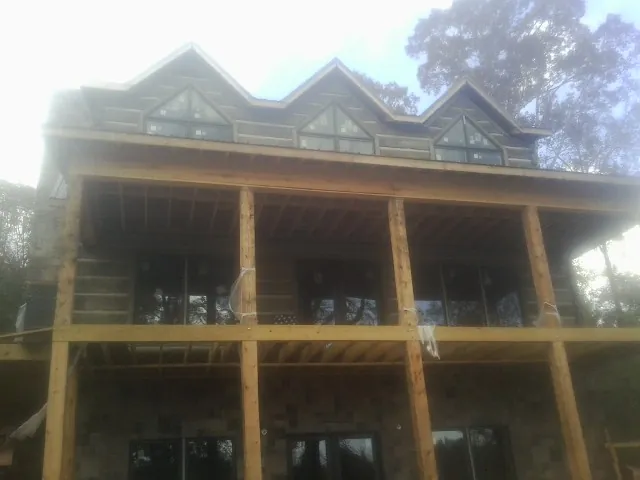 Dormers and porch framing on a large log home under construction — Roof Coating work by our crew in Minburn