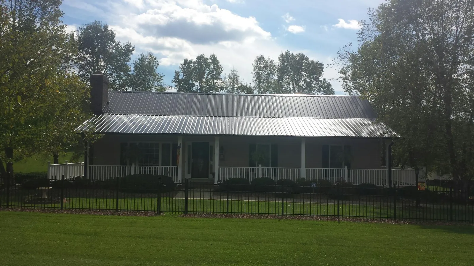 Gray metal roof on a brick ranch with a full width front porch — Gutter Guard Installation work by our crew in Minburn