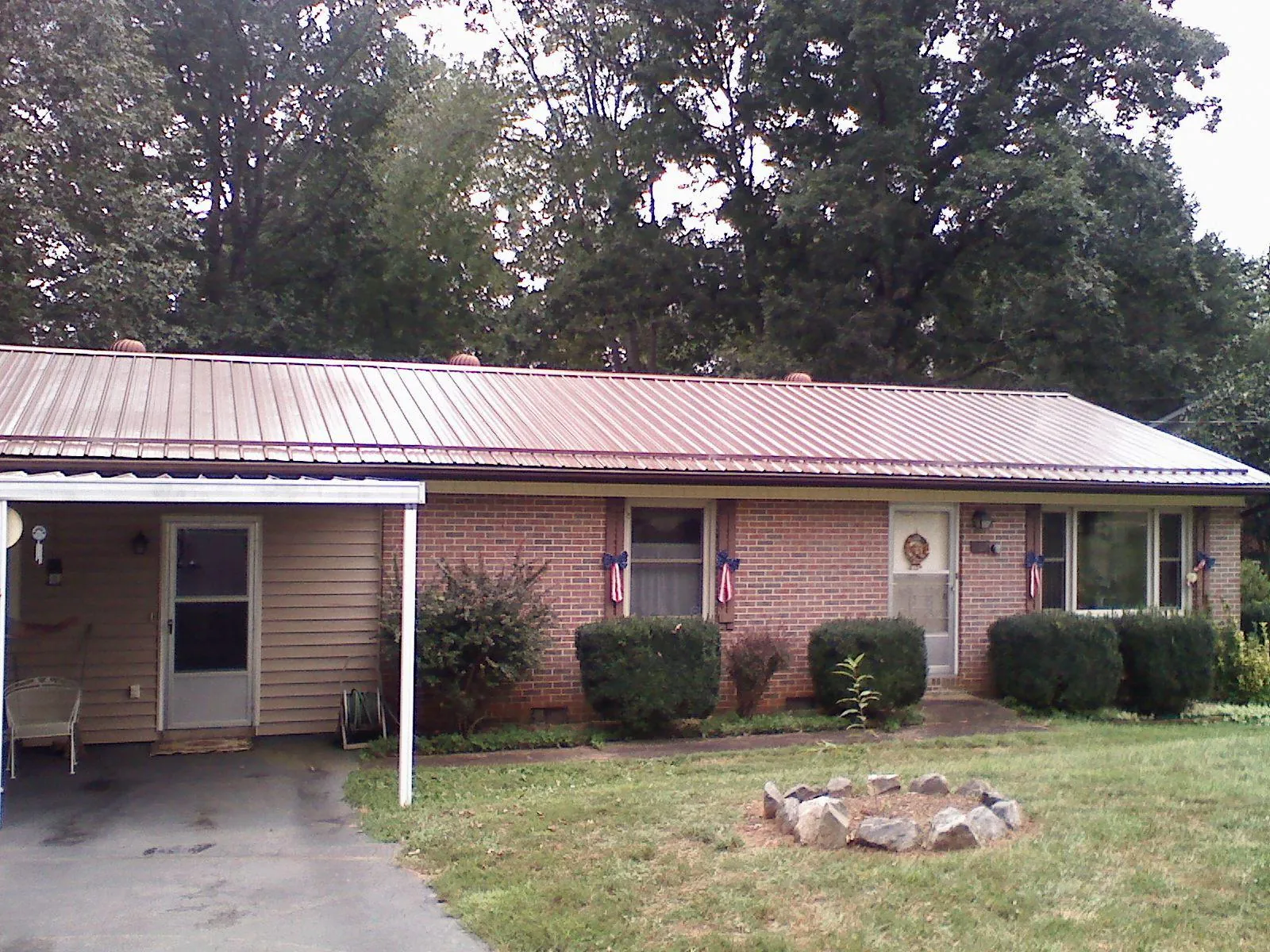 Bronze metal roof and carport on a brick ranch home — Roof Repair work by our crew in Minburn