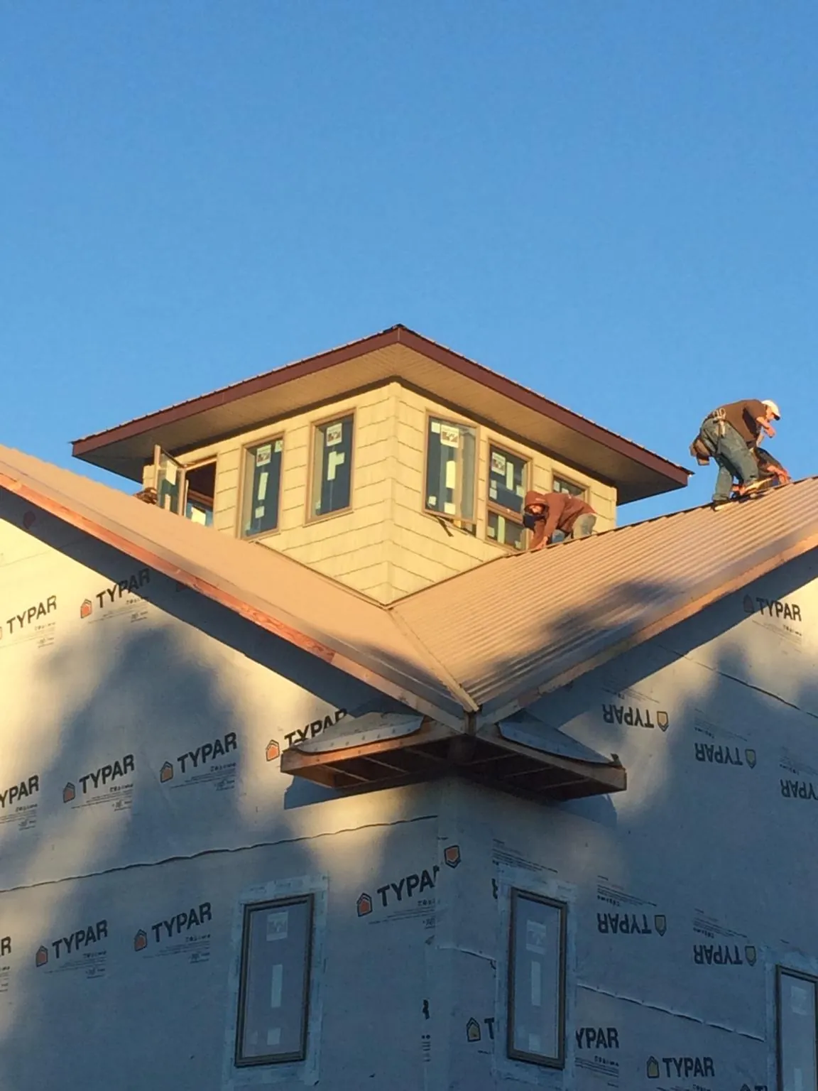 Roofers working around a rooftop cupola on a new metal roof at sunset — Roof Waterproofing in Minburn by Roofing Brothers